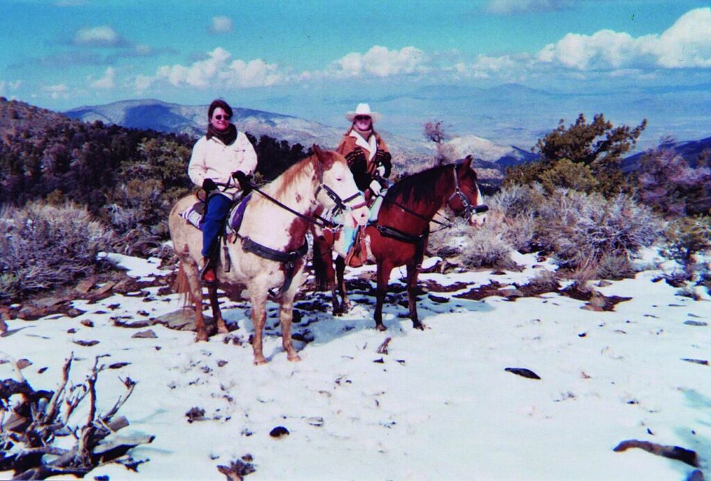 Two women sit horseback in the snow in Big Bear California